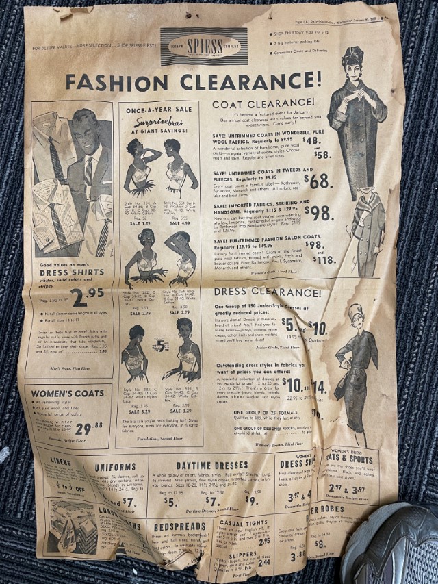 Yellowed page from a newspaper showing an ad for a department store feturing men's dress shirts, womens bras and coats and dresses