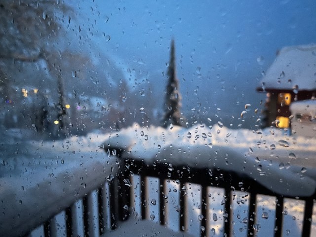 Raindrops on glass window. Background shows ski runs on a mountain across the road.